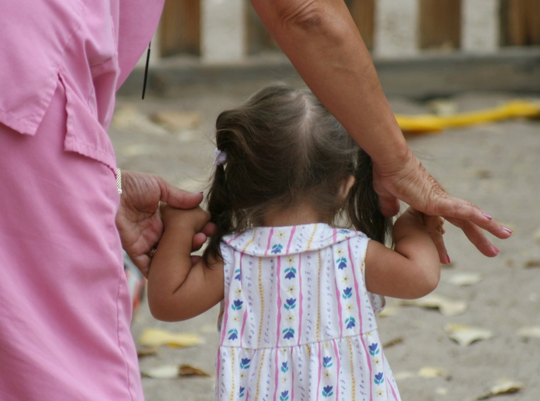 ECI staff walking toddler with white dress