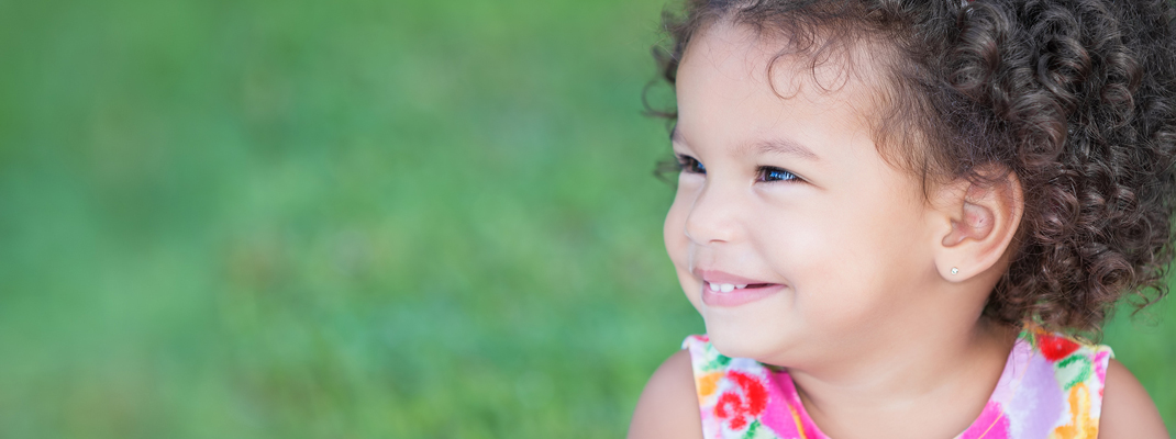 Girl in flower dress with curly hair smiling