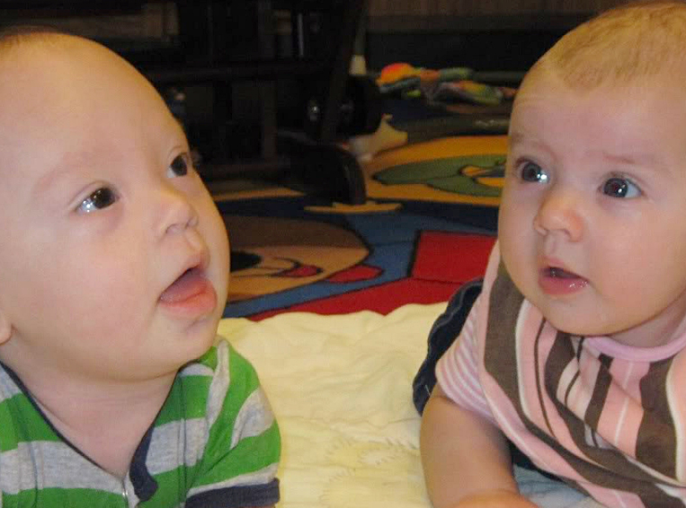 Infant girl and boy lying on their bellies on the floor