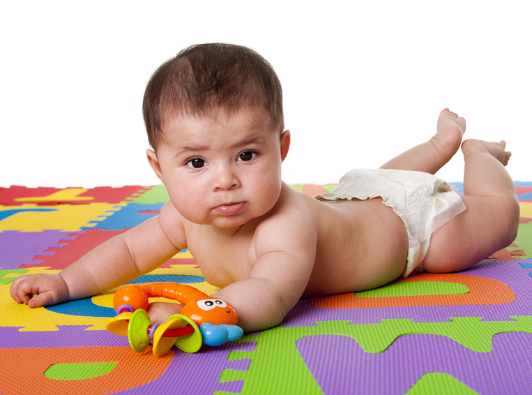 3 month infant on belly playing with rattle