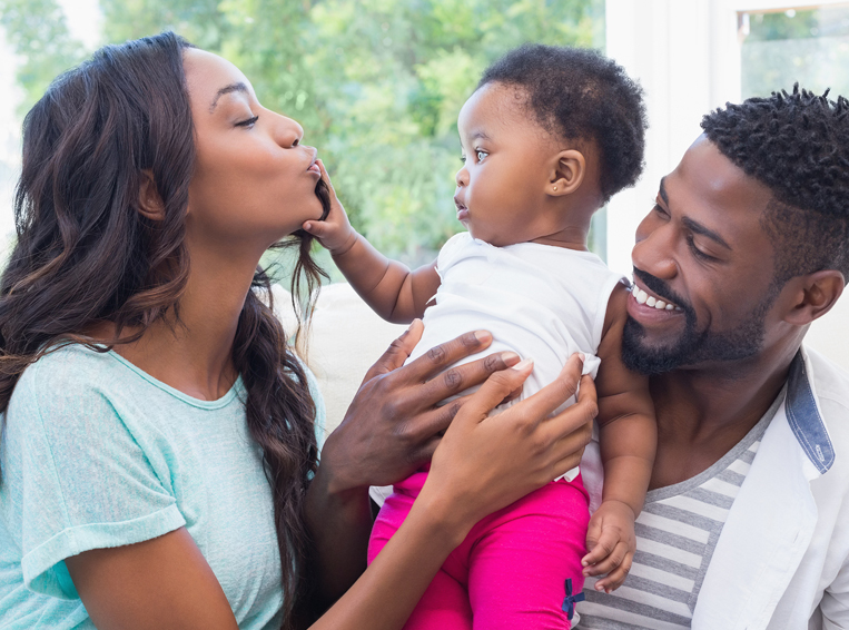 Parents holding toddler mom kissing hand