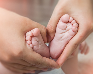 mother holding baby feet in heart pattern