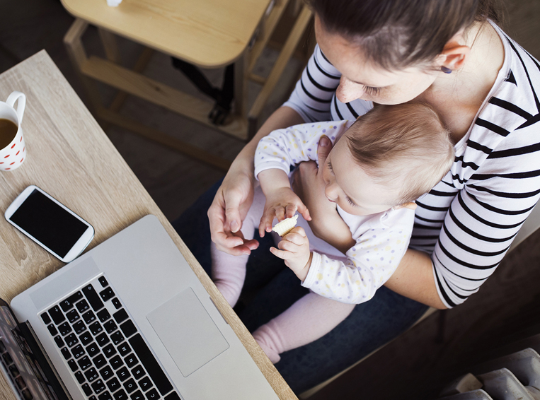 Infant sitting on Mom's lap in home office